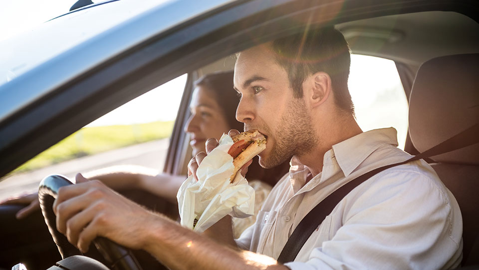 Man eating in the car while driving.
