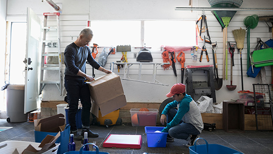 Man and teenage boy pack up a garage