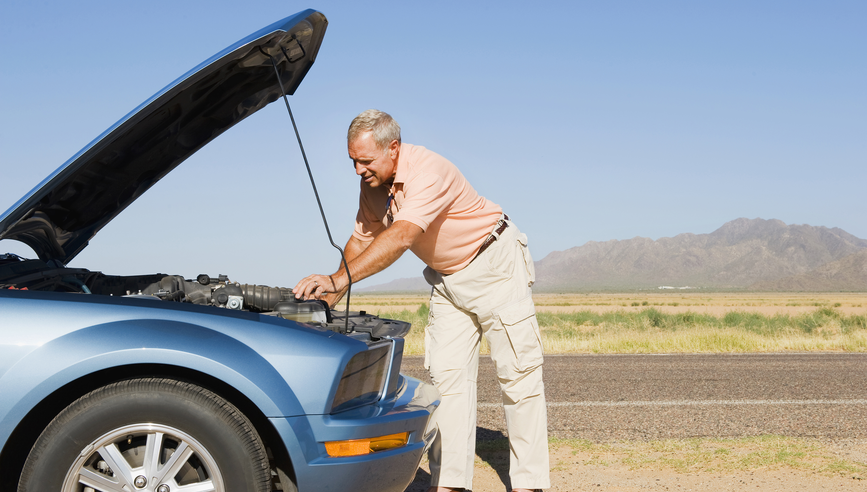 Man looking under hood of car after car breakdown.