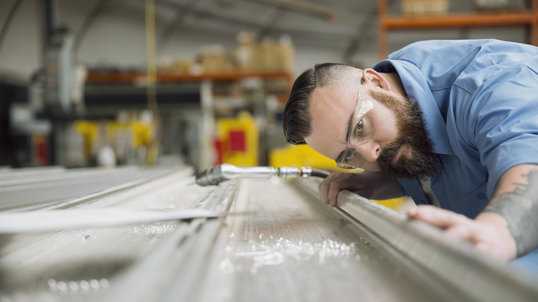 Worker examining sheet metal in manufacturing plant.