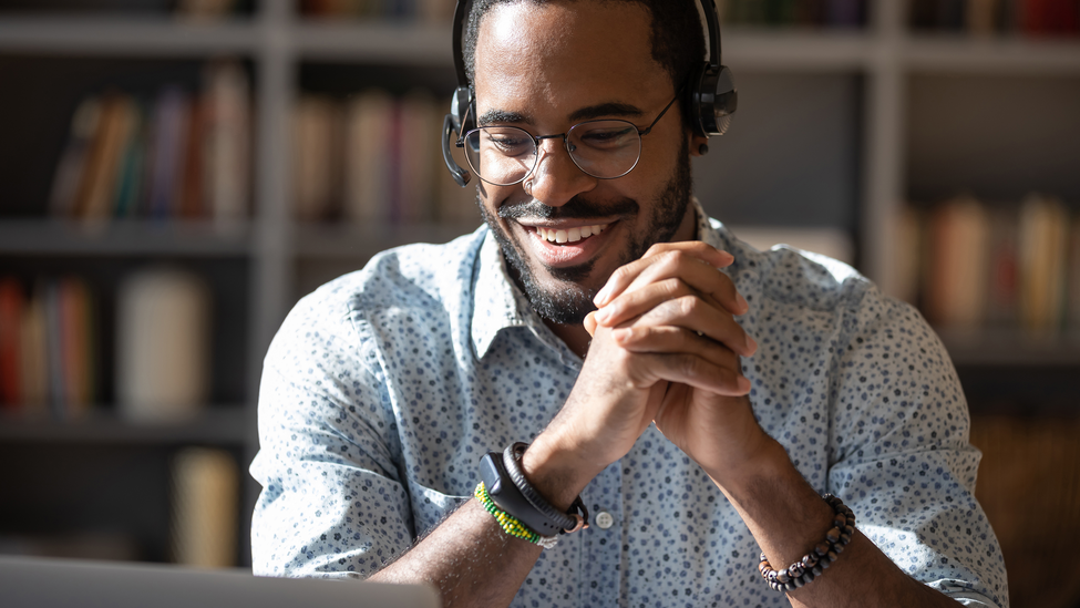 Smiling African American man in headset watch webinar or training on modern computer, happy biracial male call center agent or telemarketer work consult client online, good customer service concept