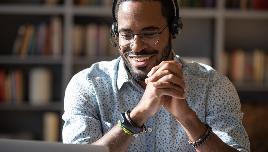 Smiling African American man in headset watch webinar or training on modern computer, happy biracial male call center agent or telemarketer work consult client online, good customer service concept