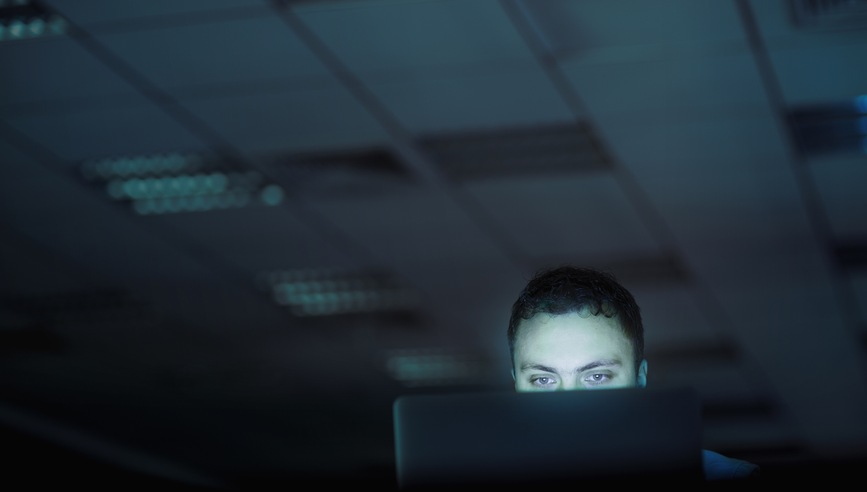 Man looking at laptop computer in office at night