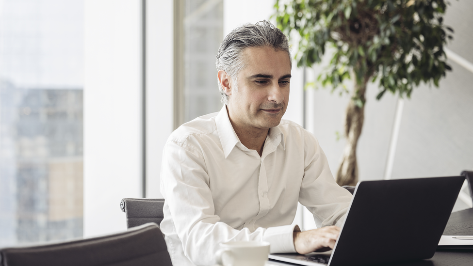 Businessman works on his laptop computer in a high rise building office.