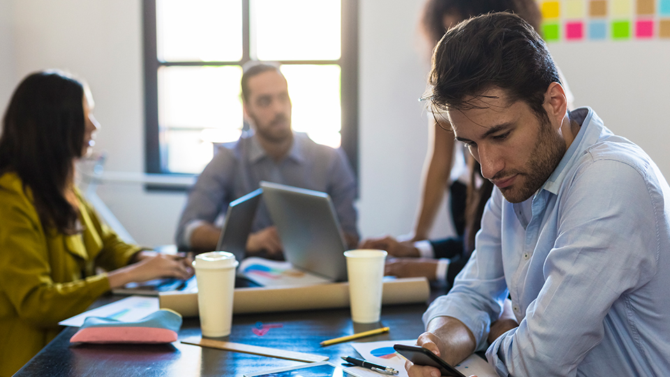 Man looking at his phone during work meeting.