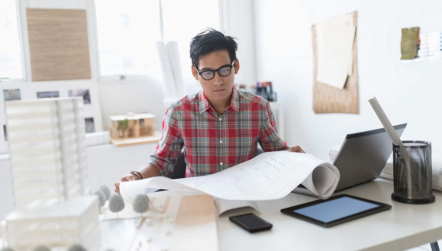 Man looking at plans at his desk.