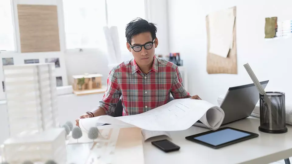 Man looking at plans at his desk.