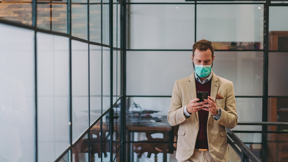 Businessman wearing mask in the office during COVID-19 pandemic; Safety in the office during COVID-19 pandemic, businesspeople with face masks