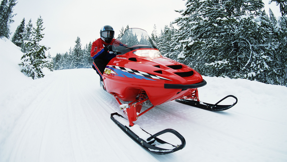 A rider on a snowmobile navigating a snowy trail.