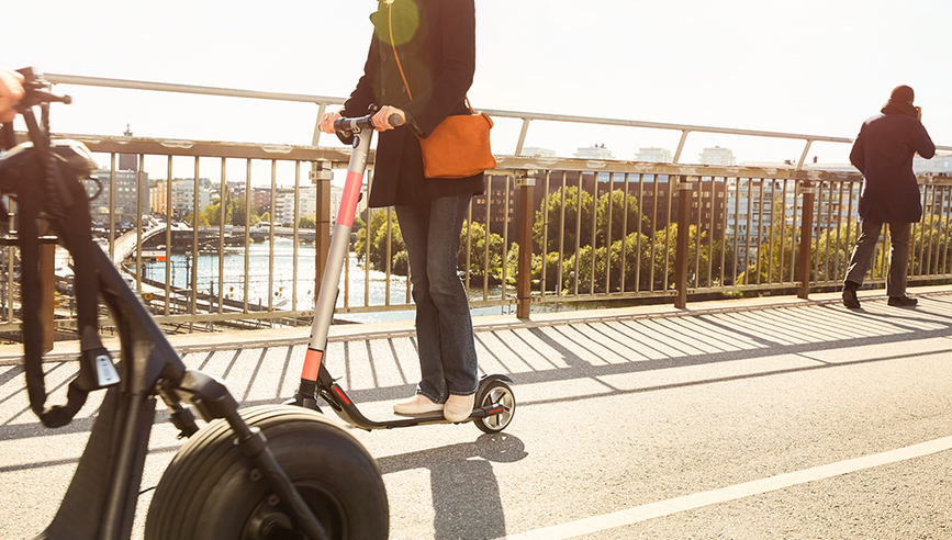 Man on street getting an e-vehicle scooter.