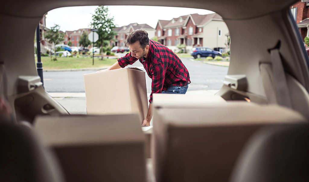 Man packing his car for moving out of his home.