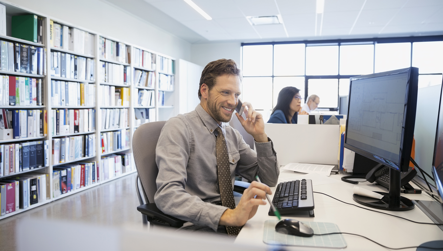 Businessman talking on cell phone at office desk