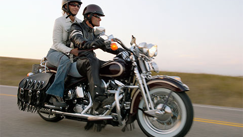 A woman riding motorcycle with a man wearing helmets