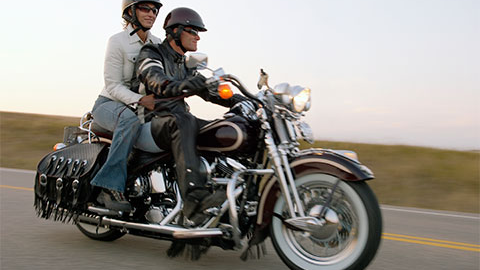 Man riding a motorcycle with a woman sitting behind him