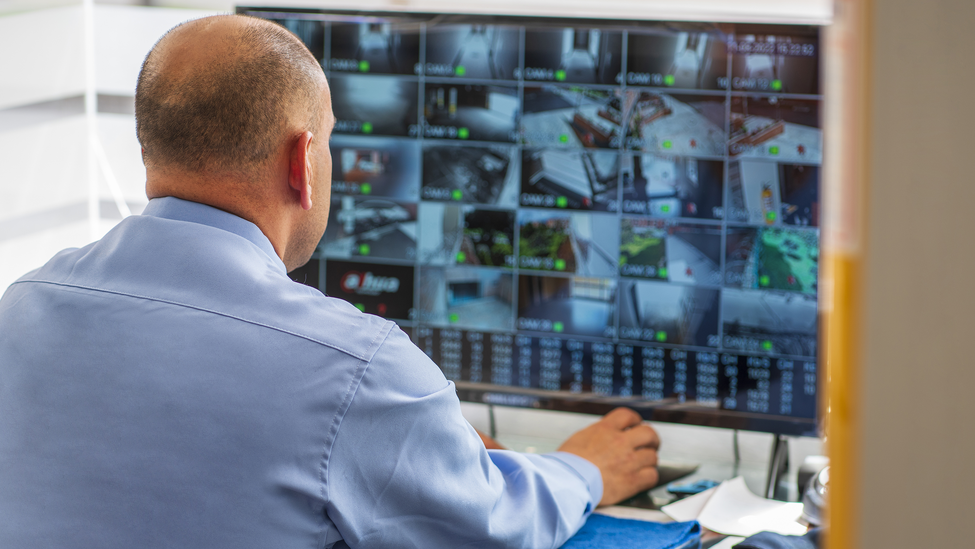 A security guard monitoring a screen in a warehouse