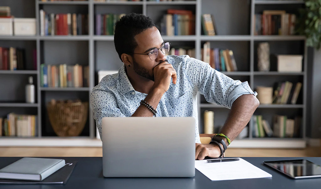 Man sitting at a desk in front of a laptop computer.