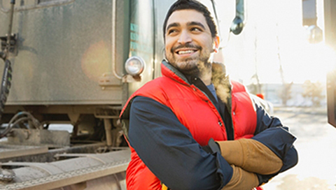 man standing beside truck, crossing his arms and smiling while looking off to the side