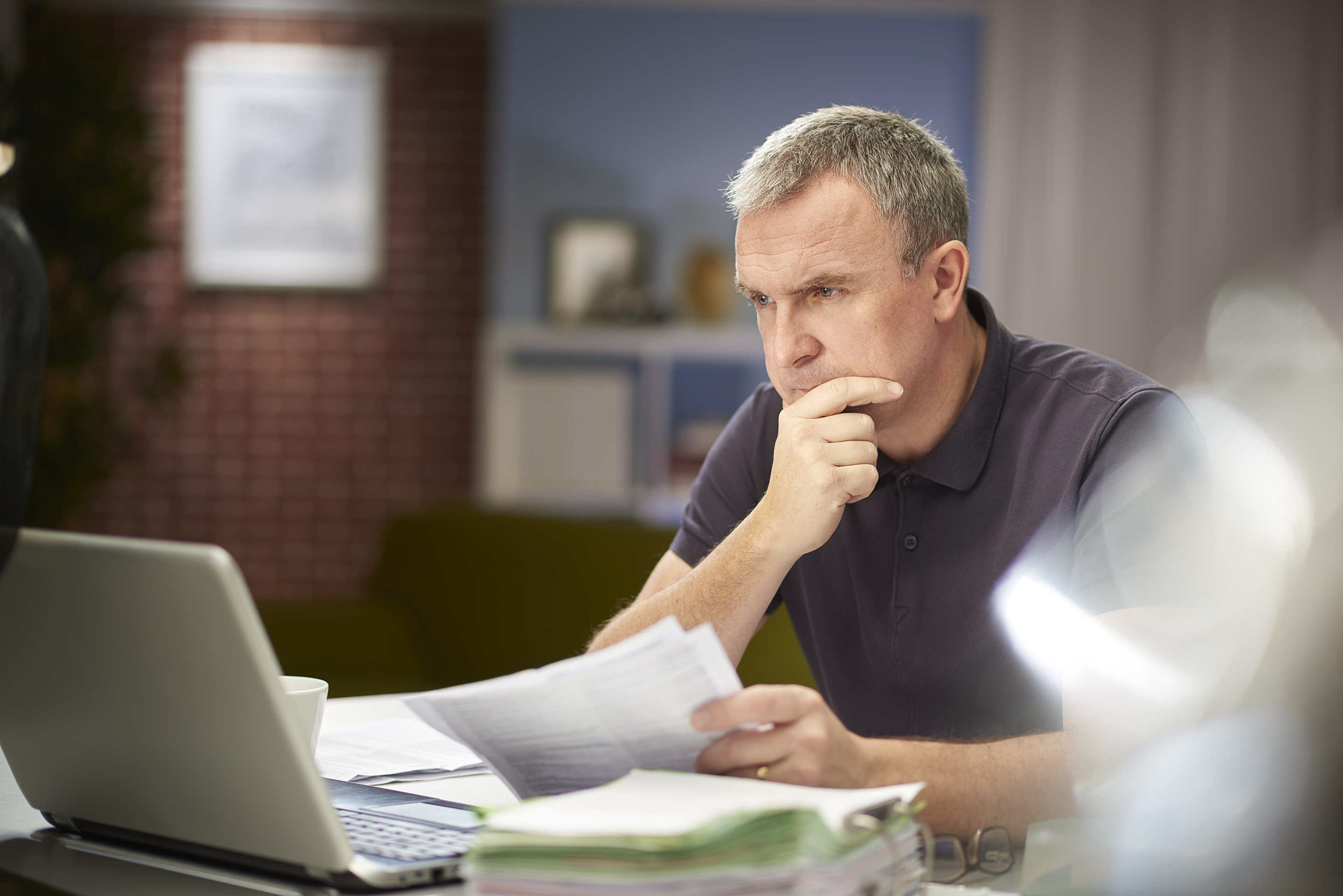 Man going over his small business paperwork with a frustrated expression.