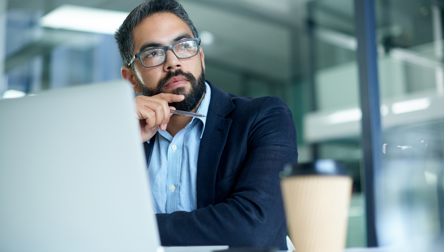 Shot of a mature businessman looking thoughtful while working on a laptop in an office; His mind always wanders to success