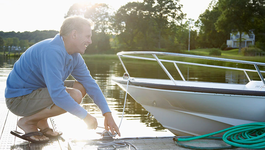 Man securing boat to dock with rope.