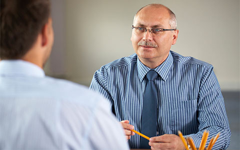 Man with glasses sits and interviews truck driver