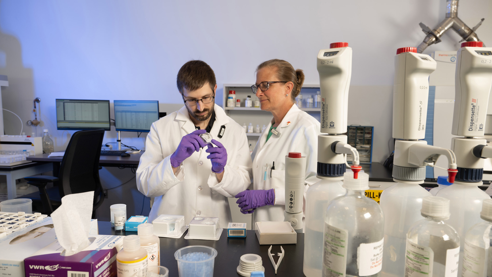 Scientist in white coat and protective gloves working with sample.