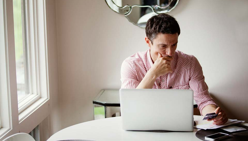 Man worried about identity theft looking at laptop.