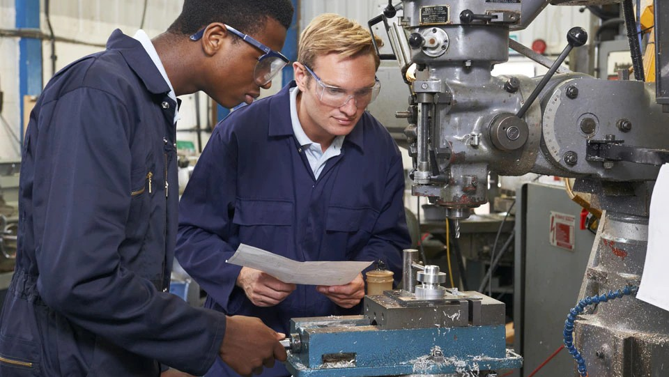 Manager onboards new manufacturing employee promoting safety.