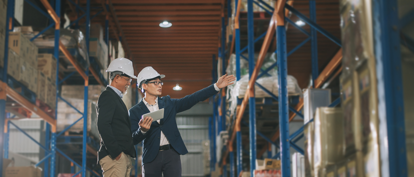 A safety director and her colleague discuss industry considerations while looking at warehouse stock.