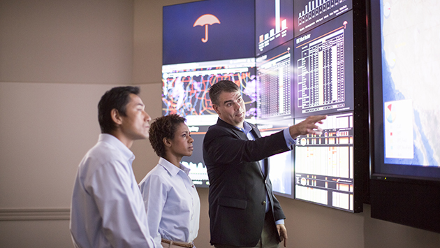 Employees analyzing graph icon on the big screen.