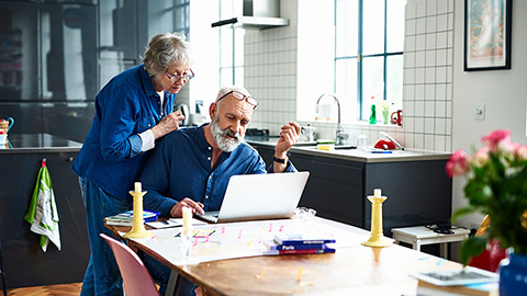 Woman and man looking at the laptop in the kitchen.