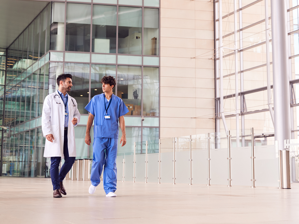 Healthcare providers discuss industry risks in front of a modern hospital.