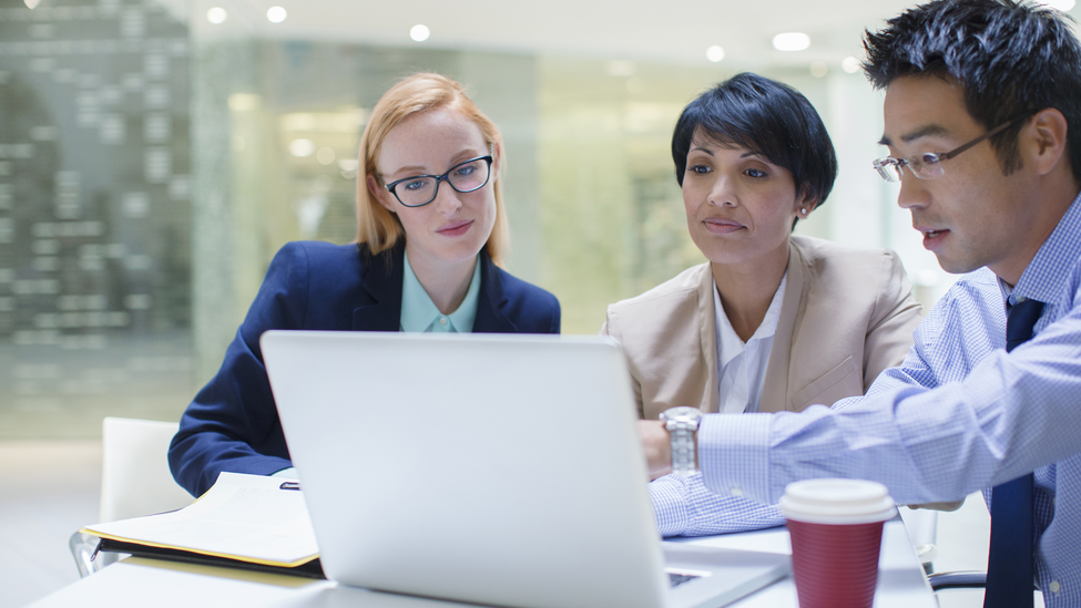 Business people gathered around laptop in office building cafe