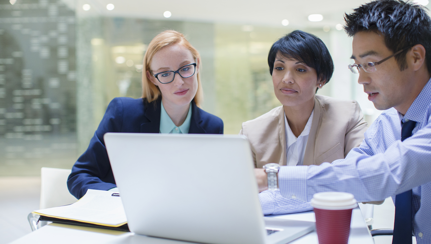 Business people gathered around laptop in office building cafe