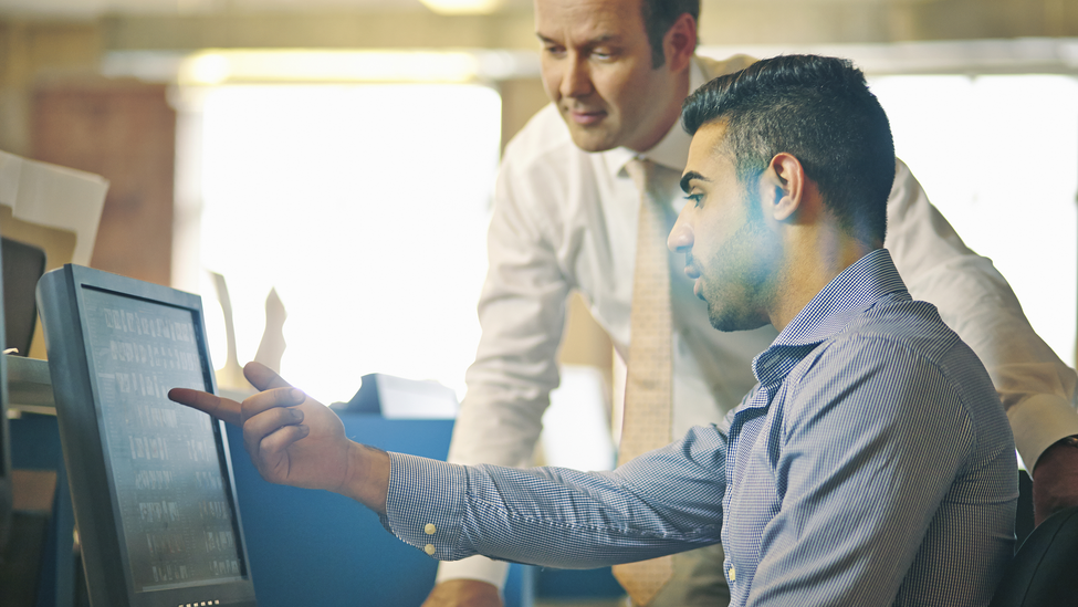 Man showing colleague work on computer screen