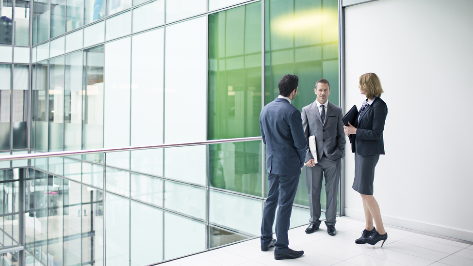 Three business people talking in the building corridor.