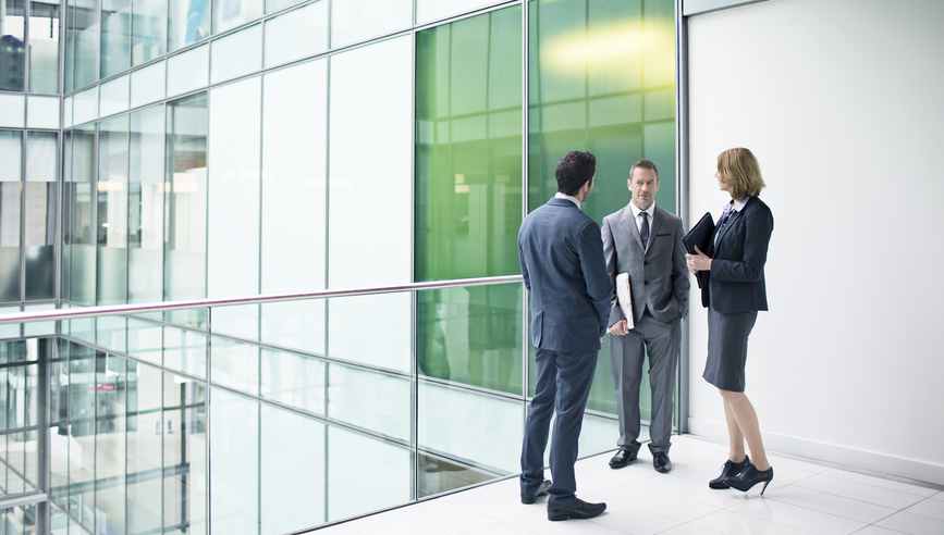 Three business people talking in the building corridor.