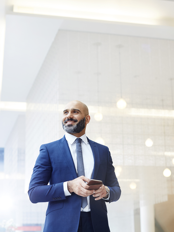 Businessperson smiles confidently in a well-lit room.