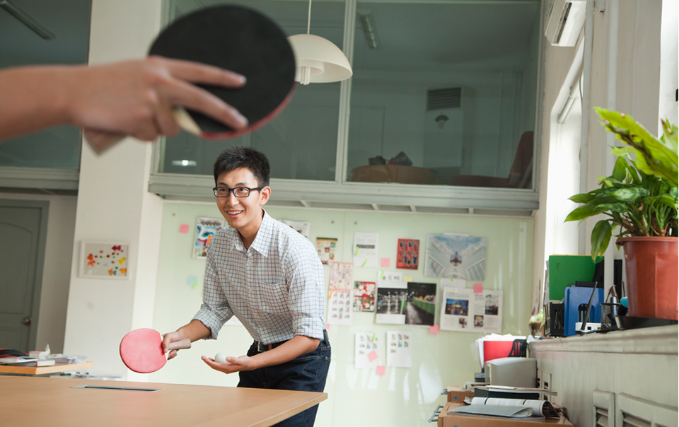 Two distracted employees playing ping pong in a modern office.