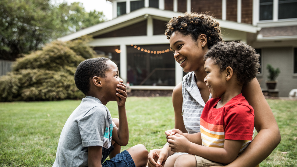 Woman with two children in front of house.