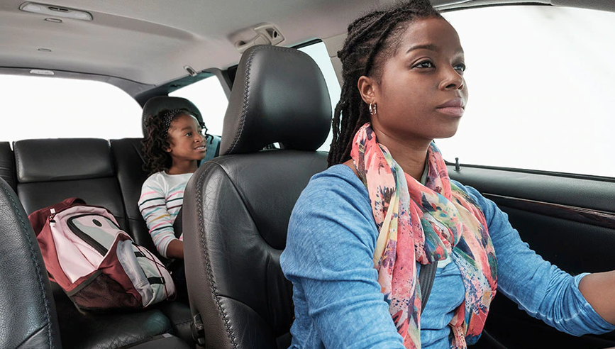 Mother driving safely with daughter in backseat.