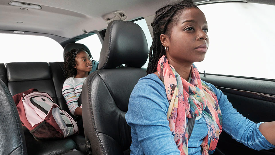 Mother driving safely with daughter in backseat.