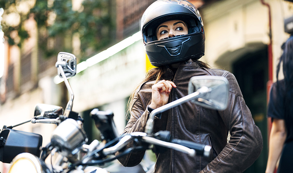 Person sitting on a motorcycle zipping up a leather jacket