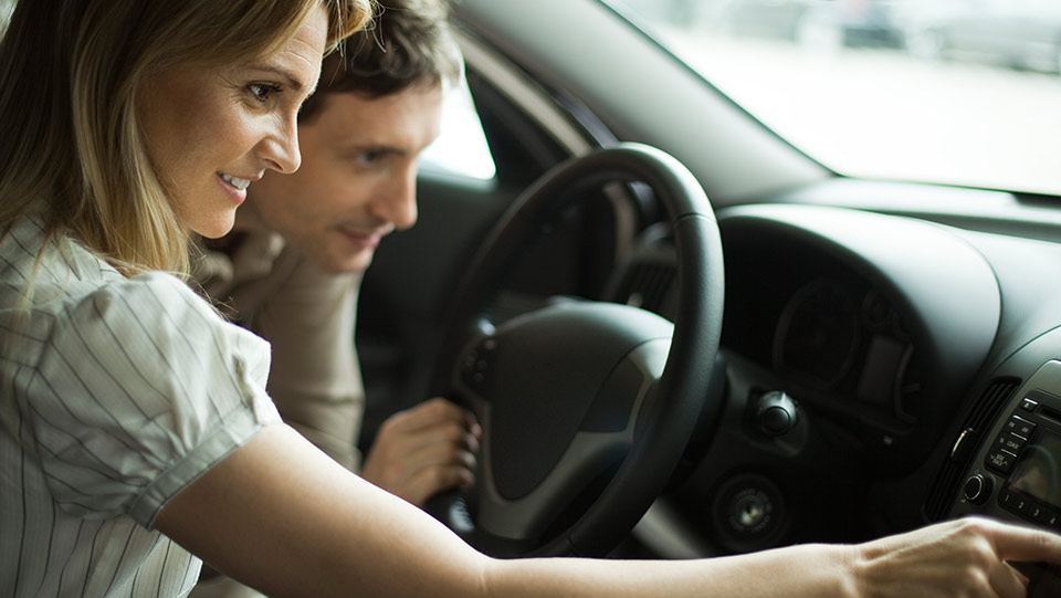 Couple testing interior features of a new car.