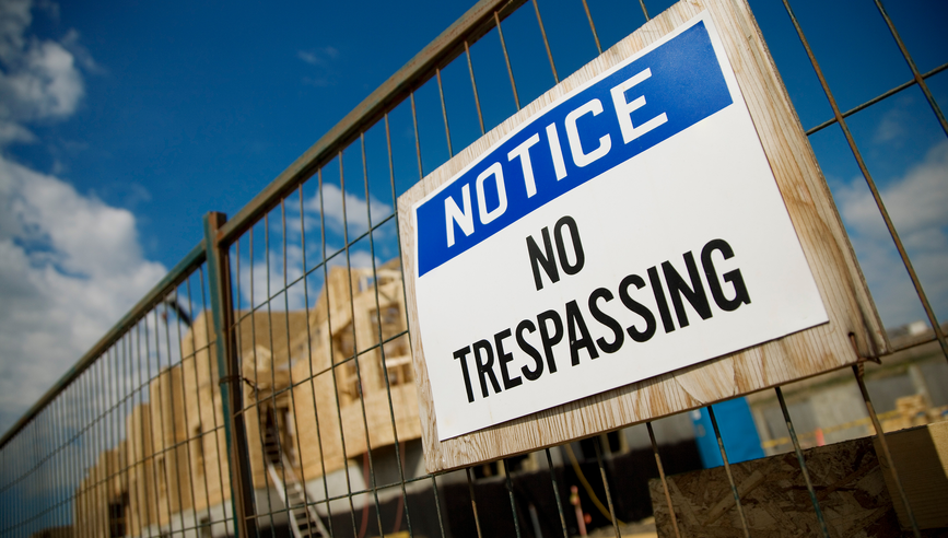 No Trespassing sign on construction site fence.