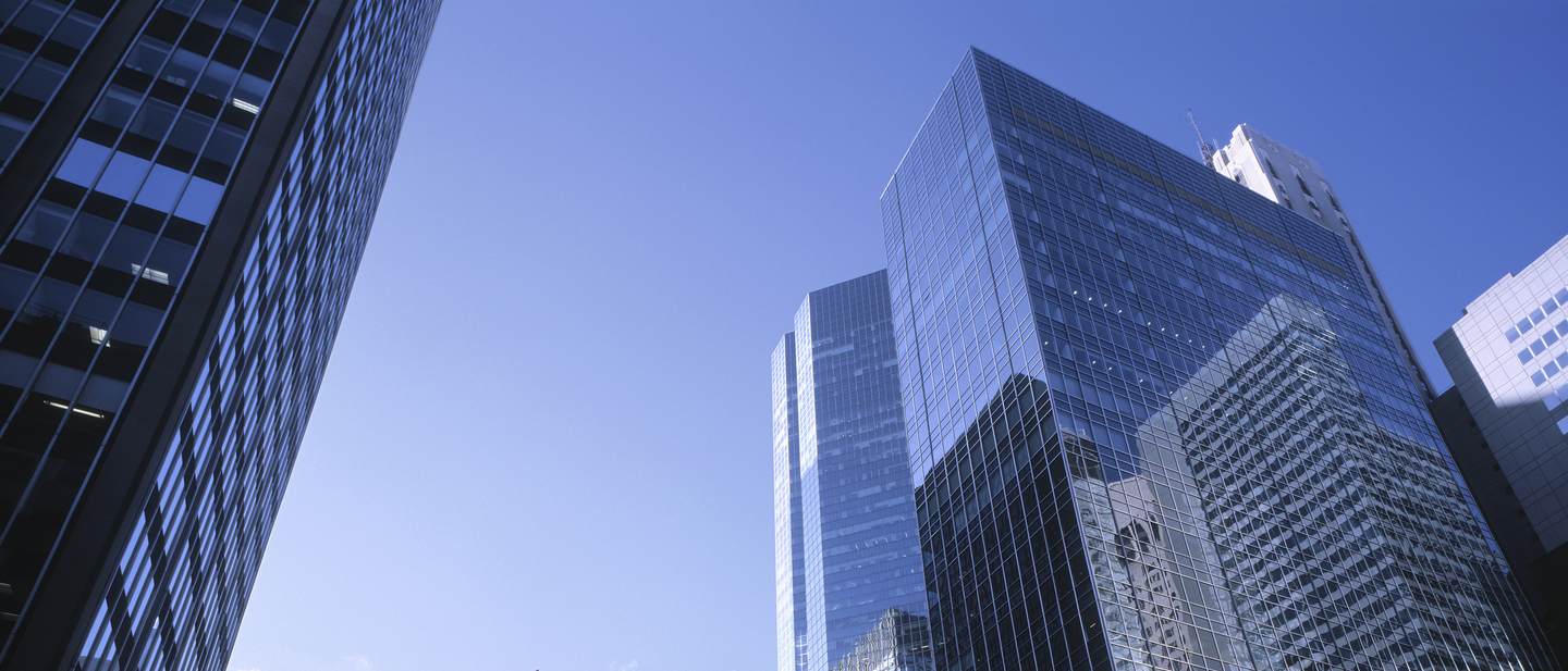 View of tall buildings in city, blue sky in background.