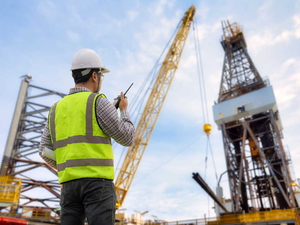 Oil industry service contractor watches as oil casing equipment gets installed.