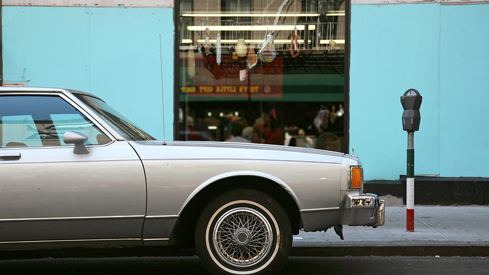 Older car parked in front of store.