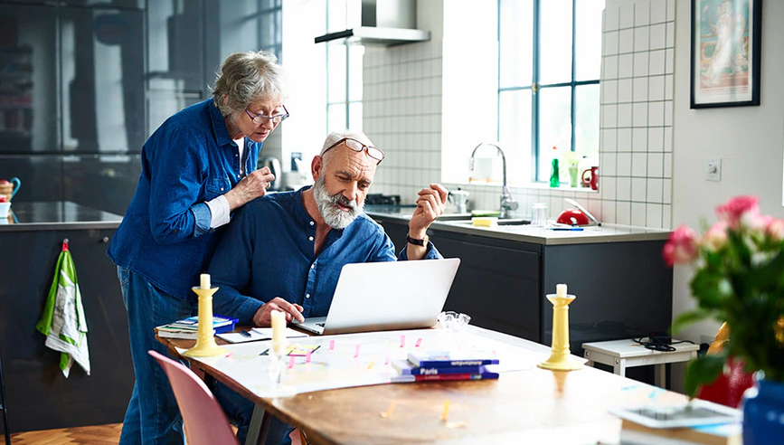 Couple looking to buy a second home on laptop on a table.