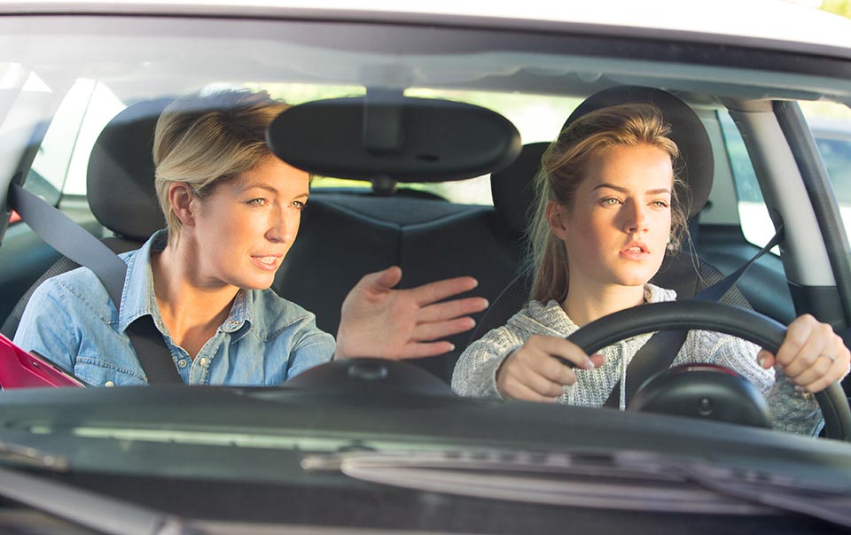 Parent and teen driving behind the wheel.